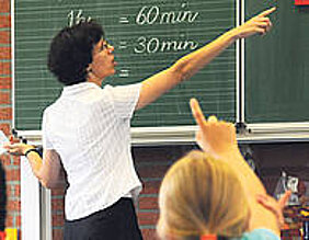 Lehrerin im Unterricht schreibend an der Tafel