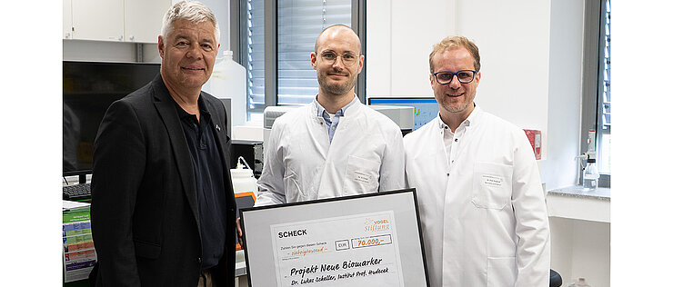 Bei der Scheckübergabe am 06. Juli 2026 am UKW-Lehrstuhl für Zelluläre Immuntherapie (von links): Gunther Schunk (Vogel Stiftung), Lukas Scheller (Universitätsklinikum Würzburg), Michael Hudecek (Universitätsklinikum Würzburg). 
