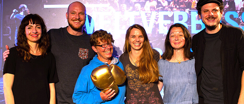 Constanze Klotz, Julien Bobineau, Gewinnerin Jennifer Timrott mit der Siegprämie, den goldenen Boxhandschuhen, Julia Schnetzer und Mitra Kassai (von links) waren beim Finale des Weltverbesserer-Science-Slams in Hamburg dabei. Rechts Moderator Rainer Holl.