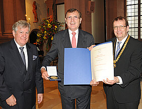 Unternehmer Baldwin Knauf bekommt von Universitätspräsident Alfred Forchel (rechts) und Vizepräsident Wolfgang Riedel die Röntgenmedaille überreicht. (Foto: Robert Emmerich)