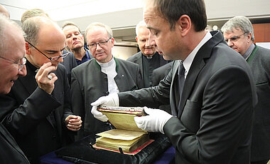 Bischof Franz Jung (2. v.l.) und das Würzburger Domkapitel drängen sich in der Universitätsbibliothek um das Kiliansevangeliar. Rechts Bibliotheksleiter Dr. Hans-Günter Schmidt.