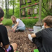 Eine Studentin verdeutlicht mit Gläsern und Wasser die Entwicklung des Niederschlags über das Jahr verteilt.