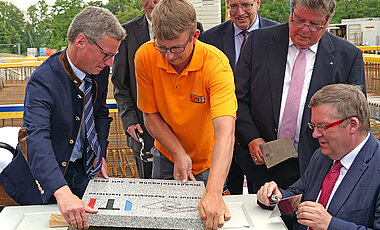 Das Verlegen des Grundsteins erfolgt unter fachmännischer Anleitung.