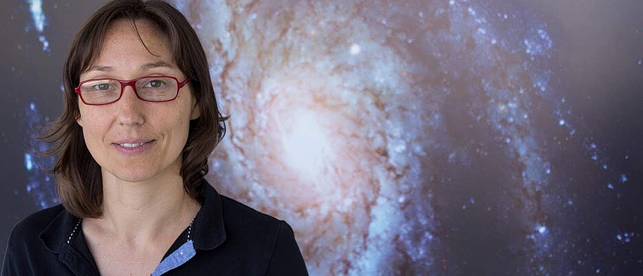 Sara Buson vor dem Bild einer Galaxis.