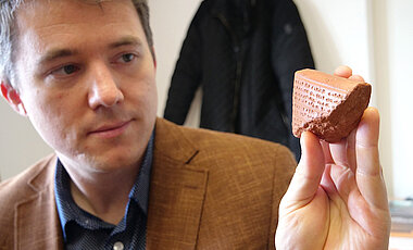 James M. Burgin mit einem typischen Beispiel einer Tontafel mit Keilschriftzeichen. Auf solchen Tafeln wurden die Annalen der Hethiter schriftlich festgehalten. (Foto: Gunnar Bartsch / Universität Würzburg)