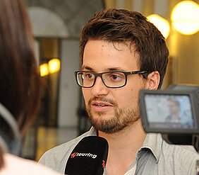 Student und IntegrAi.de-Mitbegründer Sascha Riemann erklärt die Ideen des Projektteams am Rande einer Pressekonferenz den Medien. (Foto: Uni Würzburg/Fehr)