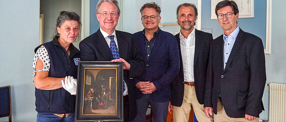 Joachim Spatz, Andreas Götz und Jan Röhrle von der Freimaurerloge „Zu den zwei Säulen an der festen Burg“ bei der Rückgabe des Gemäldes im Logenhaus. Mit im Bild: Restauratorin Ingeborg Klinger (1. v. l.) und Damian Dombrowski (3. v. l.), Direktor der Neueren Abteilung des Martin von Wagner Museums. 