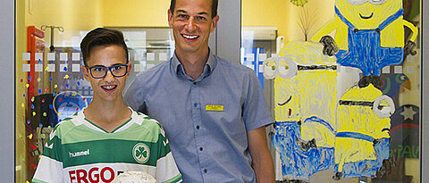 Der ehemalige MDS-Patient Lucas Melchner und Privatdozent Dr. Matthias Wölfl vor der Stammzelltherapie-Station „Schatzinsel“ der Würzburg Universitäts-Kinderklinik. (Foto: Arnika Hansen/Uniklinikum Würzburg)