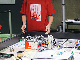 Der im Franken-Design (rot-weiß) gestaltete Roboter der „X-Rays“ holt Futter aus einem Automaten (der weiße Turm rechts im Bild) ab. (Foto: Martin Hennecke)