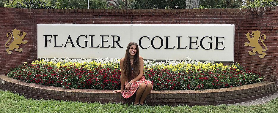 Mona vor dem Logo des Flagler College.