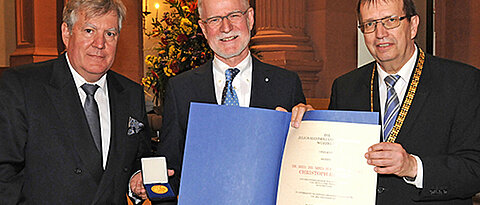 Christoph Reiners bekommt von Universitätspräsident Alfred Forchel (rechts) und Vizepräsident Wolfgang Riedel (l.) die Verdienstmedaille in Gold überreicht. (Foto: Robert Emmerich)