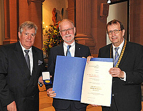 Christoph Reiners bekommt von Universitätspräsident Alfred Forchel (rechts) und Vizepräsident Wolfgang Riedel (l.) die Verdienstmedaille in Gold überreicht. (Foto: Robert Emmerich)