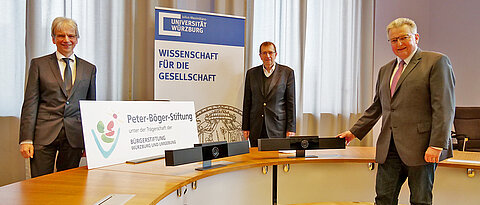 Die Stiftungsvorstände Rainer Wiederer (links) und Lothar Wegener (rechts) beim Austausch mit Unipräsident Alfred Forchel. Auf dem Tisch sind zwei der neuen Konferenz-Systeme zu sehen.