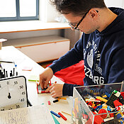 Der Teilnehmer Tobias Haase ist dabei, durch das Zusammenbauen von Lego, eine Aufgabe zu lösen.