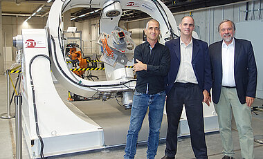 Die ERC-Synergy-Grant-Preisträger Ilan Koren, Yoav Schechner und Klaus Schilling vor dem Präzisions-Bewegungssimulator am Zentrum für Telematik in Würzburg. 