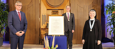 Schwester Maria Monika Edinger bekam die Ehrenbürgerinwürde verliehen. Ihr gratulierten  Laudator und Uni-Kanzler Uwe Klug (l.) sowie Unipräsident Paul Pauli.