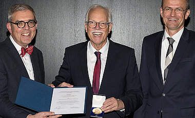 Joachim Fuchs (Mitte) bei seiner Ehrung. Links Matthias Frosch, Dekan der Medizinischen Fakultät, rechts Jens Maschmann, Ärztlicher Direktor des Universitätsklinikums.