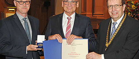 Karl Südekum bekommt von Universitätspräsident Alfred Forchel (rechts) und Kanzler Uwe Klug die Verdienstmedaille in Silber überreicht. (Foto: Robert Emmerich)