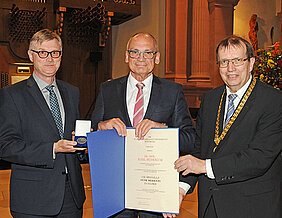 Karl Südekum bekommt von Universitätspräsident Alfred Forchel (rechts) und Kanzler Uwe Klug die Verdienstmedaille in Silber überreicht. (Foto: Robert Emmerich)