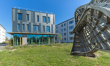 Außenansicht des Neubaus am Campus Hubland Nord mit dem Kunstobjekt „Ennepersche Minimalfläche“ aus der Reihe „Kunst am Bau“.