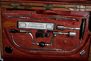 Instrumentenkasten eines reisenden Chirurgen, ca. 1850, französische Fabrikation. In der Mitte Kronentrepan und Handtrepan, darunter Metallrohre zum Einführen in die Blase.