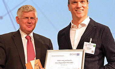 Andreas Hochhaus, der Vorsitzende der Deutschen Gesellschaft für Hämatologie und Onkologie, überreichte den Artur-Pappenheim-Preis 2022 an Leo Rasche (rechts).