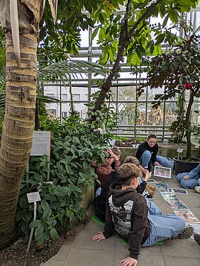 Eine Studentin erarbeitet mit den Schüler:innen die Schritte der Kakaoernte.