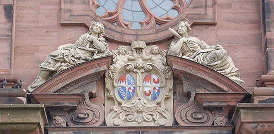 Über dem Westportal der Neubaukirche räkeln sich Justitia und Sapientia. Die zwei Figuren aus Sandstein wurden 1999 restauriert. Foto: Robert Emmerich